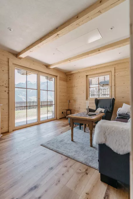 Wohnzimmer mit Holzwänden und großen Fensterelementen