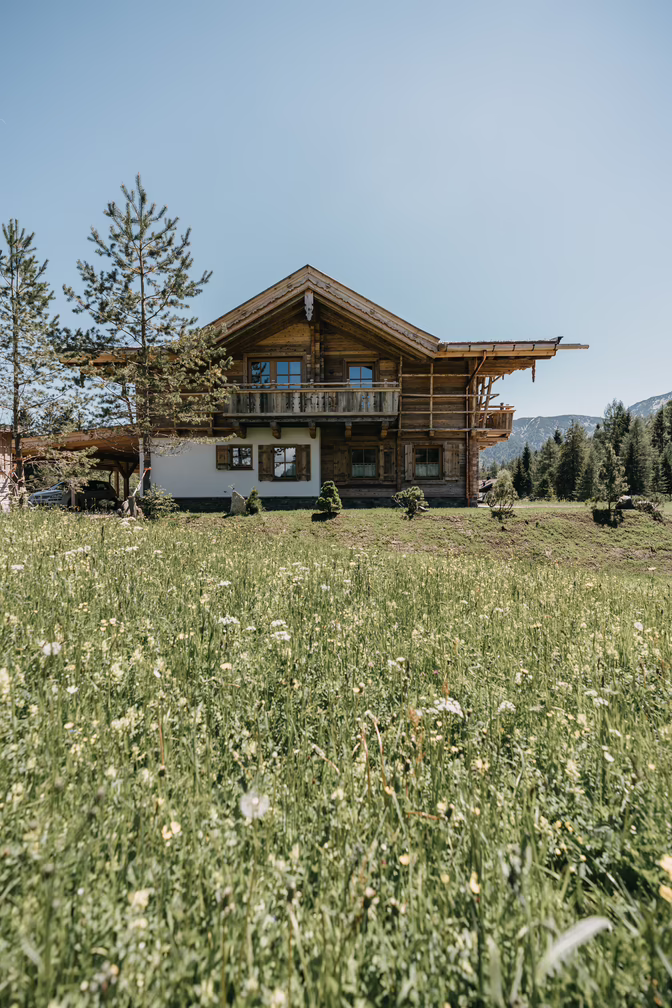 Vollholzhaus umgeben von Wiesen und Wäldern